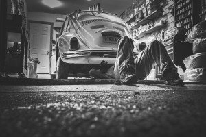 Person working under old VW Bug in a garage