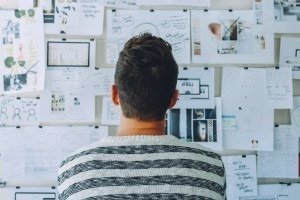 Man looking at idea board with printed diagrams pinned to it