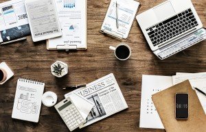 Overhead photo of desk with laptop, coffee, and business planning material